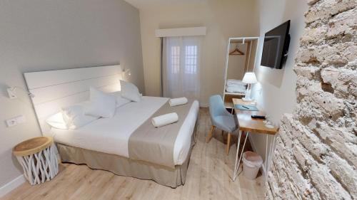 a bedroom with a bed and a desk with a television at Madeinterranea Suites in Málaga