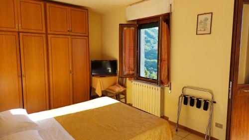 a bedroom with a bed and a window and a television at Amelia Hotel in Momigno