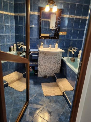 a blue tiled bathroom with a sink and a tub at Casa/camere Maria in Corbu