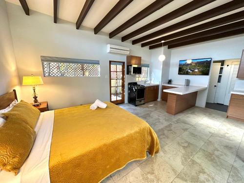 a bedroom with a large yellow bed and a kitchen at Atrium Palm Springs - G A Y mens Resort in Palm Springs