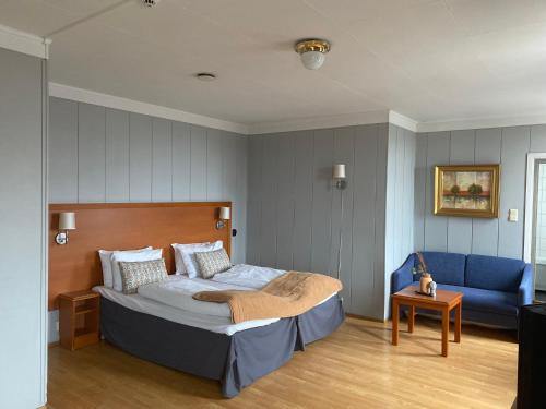 een slaapkamer met een bed en een blauwe bank bij Horten Budget Hotel in Horten