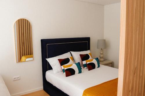 um quarto com uma cama com almofadas coloridas em Fish Village Deluxe em Vila Nova de Gaia