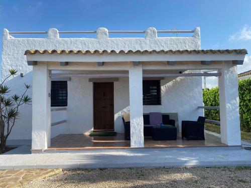 Cette maison blanche dispose d'une terrasse couverte et d'une porte en bois. dans l'établissement Kalma experiencias turísticas, à Cadix