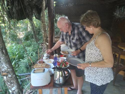 Un uomo e una donna che preparano il cibo a tavola di Riverston Du Eco Cottage a Rattota