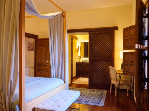 a bedroom with a bed and a desk with a chair at Casa del Armiño Mansión de la Familia de "El Greco" in Toledo