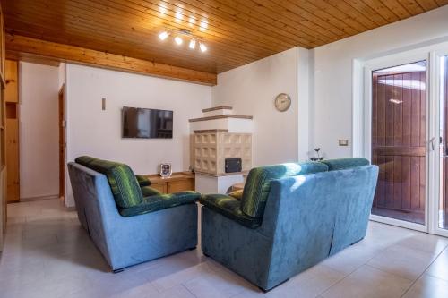two blue chairs in a living room with a tv at DolomiApartments - Casa Lagorai in Predazzo