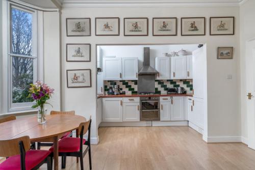 a kitchen with white cabinets and a table with chairs at ALTIDO Eclectic flat with Garden in London