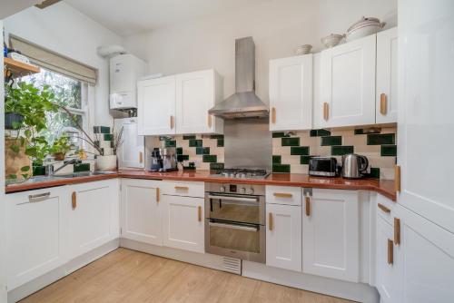 a kitchen with white cabinets and a stove at ALTIDO Eclectic flat with Garden in London