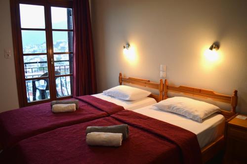 a bedroom with two beds with red sheets and a window at Pension Mando in Skiathos