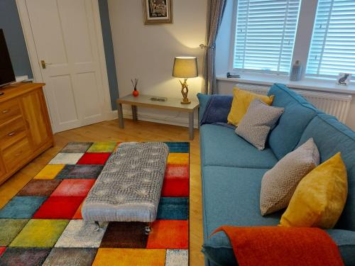 a living room with a blue couch and a colorful rug at Black Cat Cottage in Moffat