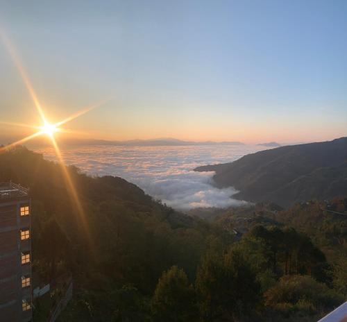 a view of the sun rising over the mountains with clouds at Mountain Resort in Nagarkot