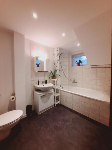 a white bathroom with a tub and a sink at Gemütliches Apartment am Gottesberg in Muldenhammer