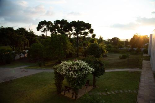 a view of a park with a bench and flowers at Pousada Bom Pastor in Caxias do Sul