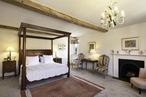 a bedroom with a canopy bed and a fireplace at Butley Priory Farmhouse in Woodbridge