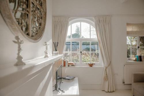 Habitación blanca con ventana grande y mesa. en Butley Priory Cottage en Woodbridge