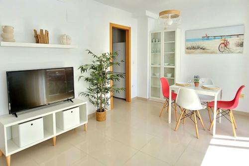 ein Wohnzimmer mit einem TV, einem Tisch und Stühlen in der Unterkunft Appartement El Campello plage in El Campello