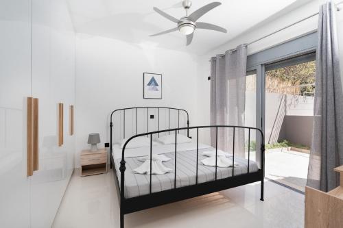 a bedroom with a bed and a ceiling fan at Luna Apartment by A&D Properties in Porto Rafti