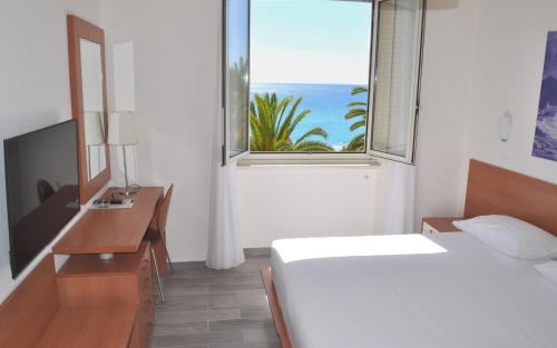 a bedroom with a bed and a desk and a window at Hotel Boncardo in Finale Ligure