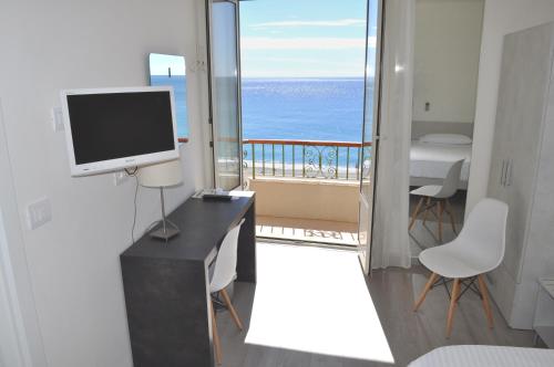 a room with a desk with a television and a balcony at Hotel Boncardo in Finale Ligure