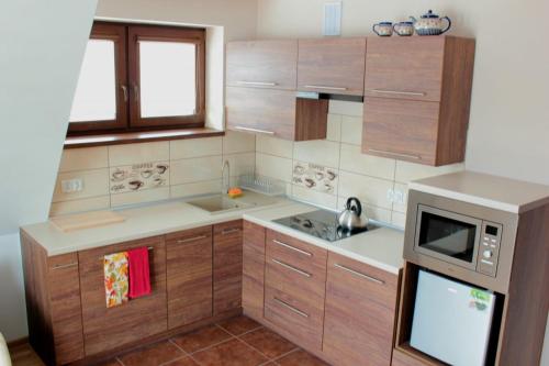 een kleine keuken met houten kasten en een magnetron bij Villa TATRIA in Witów