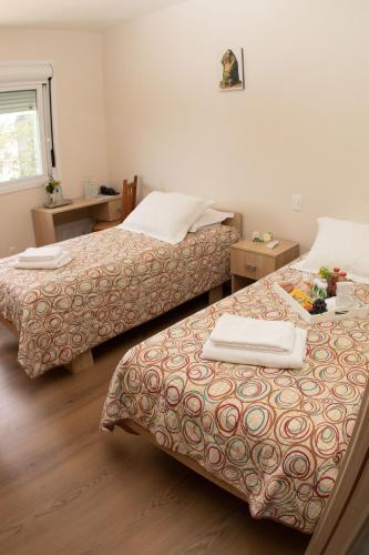 two beds in a room with two tables at Pousada Bom Pastor in Caxias do Sul