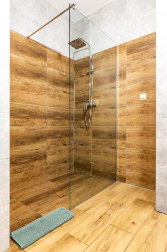 a shower with a glass door and a wooden floor at Apartament 66 Zator in Zator