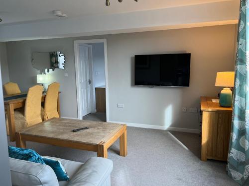 a living room with a table and a tv on a wall at Impeccable 1-Bed Apartment in Ulverston in Ulverston