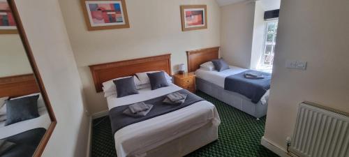 a hotel room with two beds and a mirror at The Stables at The George Of Wilby in Wellingborough