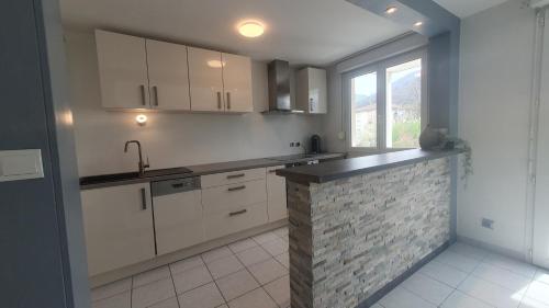 a kitchen with white cabinets and a brick wall at Bel appt au cœur des vallées in Albertville