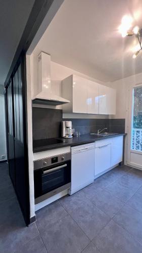 une cuisine avec des armoires blanches et un four à plaques de cuisson dans l'établissement Joli T2 proche plage et parking privé, à Bandol