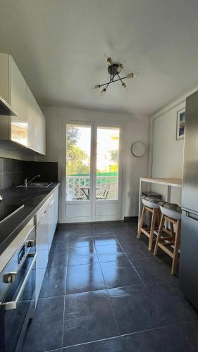 une cuisine avec des placards blancs et une grande fenêtre dans l'établissement Joli T2 proche plage et parking privé, à Bandol