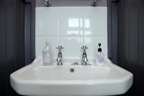 a bathroom sink with two bottles of soap and a window at An Riasc B&B in Ballydavid