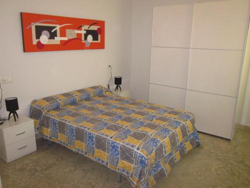 1 dormitorio con 1 cama y una pintura en la pared en Apartamento ideal en Guadix