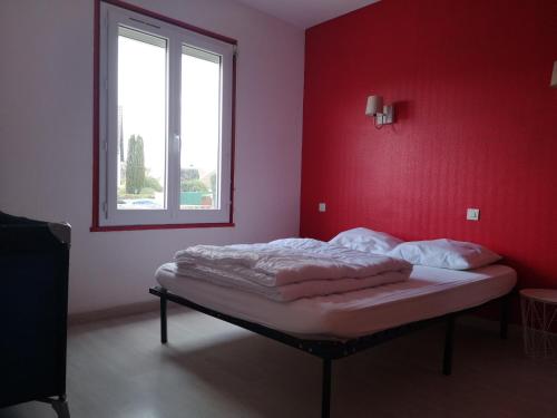 een slaapkamer met een bed met een rode muur bij MAISON A 10MIN DU ZOO DE BEAUVAL in Noyers-sur-Cher
