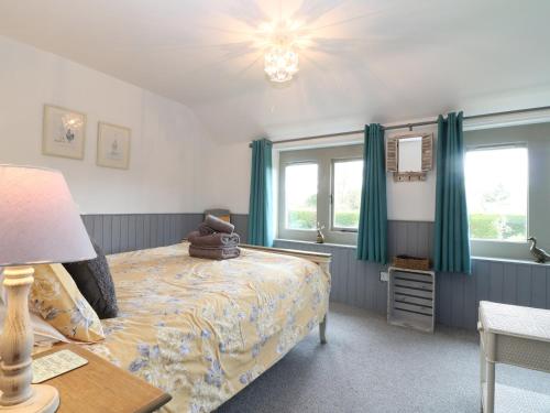 Schlafzimmer mit einem Bett und grünen Vorhängen in der Unterkunft Honeystone Cottage in Moreton-in-Marsh