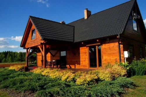 een grote houten hut met een zwart dak bij Uroczy drewniany dom w ciszy i spokoju in Redułty