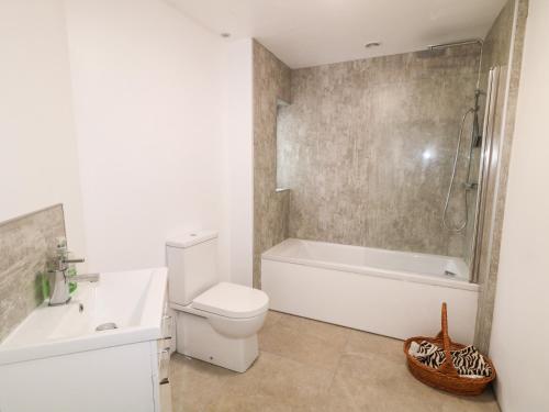 a bathroom with a tub and a toilet and a sink at The Poets Cottage in Ballymena