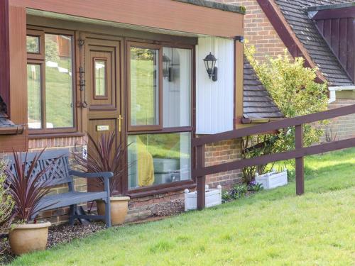 a house with a bench next to a fence at Lilyrose Cottage in Pevensey