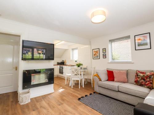 a living room with a couch and a flat screen tv at Lilyrose Cottage in Pevensey