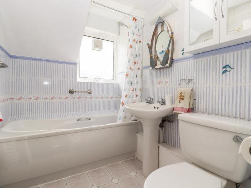y baño con bañera blanca, lavabo y aseo. en Lilyrose Cottage, en Pevensey