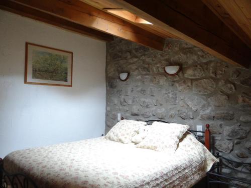 a bedroom with a bed in a stone wall at LE MYRO in Péreyres