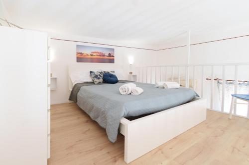 a white bedroom with a bed with two towels on it at Casa sul molo in Cefalù