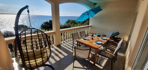 a balcony with a table and chairs and an umbrella at Comfortable family apt Iris 20m from beach in Mandre in Mandre