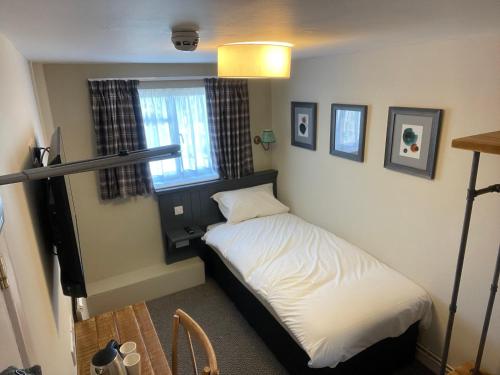 a small bed in a room with a window at The Bull Hotel in Downton