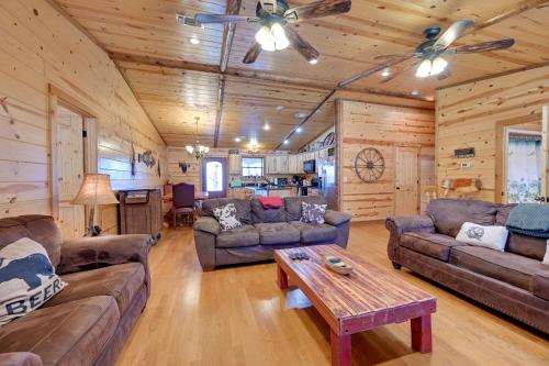 a living room with couches and a table in a cabin at Broken Bow Cabin with Hot Tub and Covered Deck! in Stephens Gap