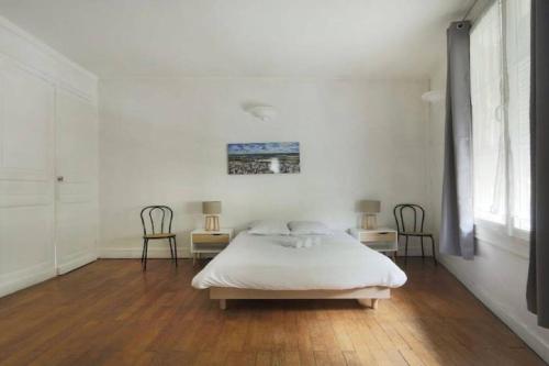 a white bedroom with a bed and two chairs at Point calme & stratégique de Tours in Tours