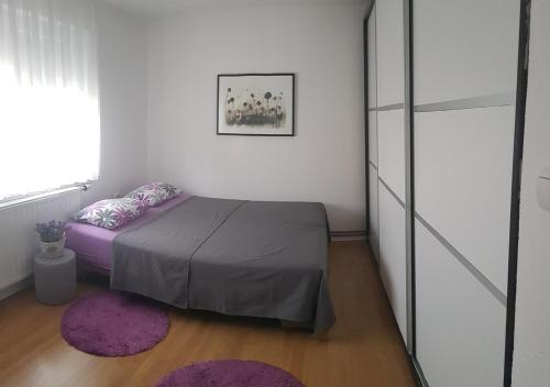 a bedroom with a bed with purple sheets and a window at Apartman Hamad, Bihać in Bihać