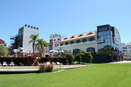 un edificio con patio y césped frente a él en Hotel El Condado en Villa Carlos Paz