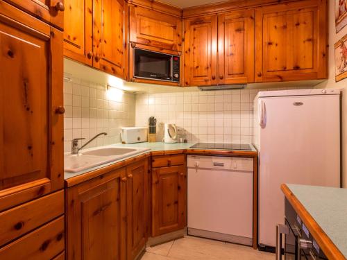 une cuisine avec des armoires en bois et un réfrigérateur blanc dans l'établissement Appartement spacieux pour 6, proche pistes et centre aquasportif à Val-d'Isère - FR-1-694-194, à Val dʼIsère