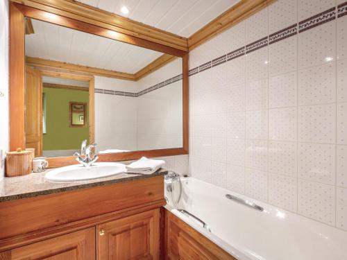 une salle de bain avec un lavabo, une baignoire et un miroir dans l'établissement Appartement de standing avec cheminée et parking en haut des pistes - FR-1-694-247, à Val dʼIsère